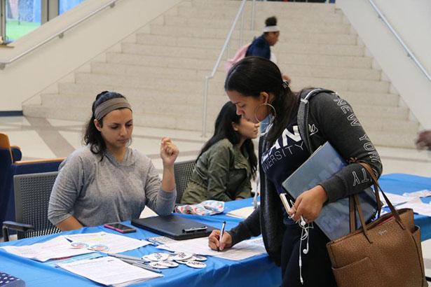 Female presenting student filling out a voter registration form