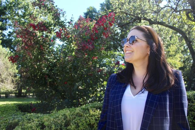 This is an image of Ashley Buchanan at Liberty Hall Academic Center walking in the garden wearing sunglasses