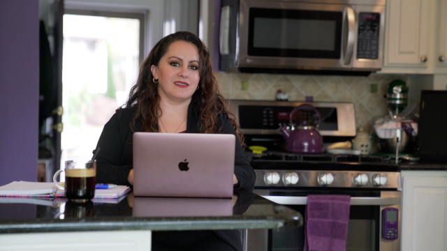 A Kean Online student with a laptop in her kitchen.
