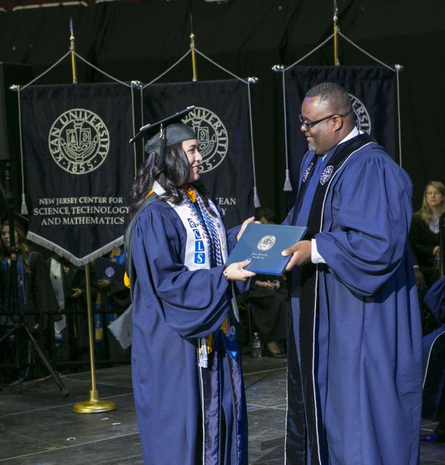 Repollet hands a Kean grad her diploma