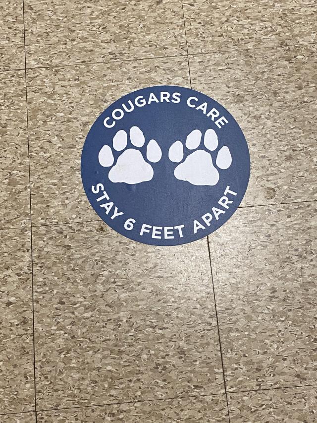 Photo of cougar care floor sticker reminging people to stay 6 ft apart