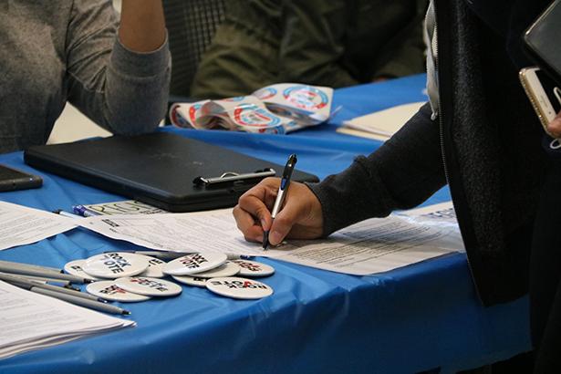 A closeup of a student registering to vote at a desk.