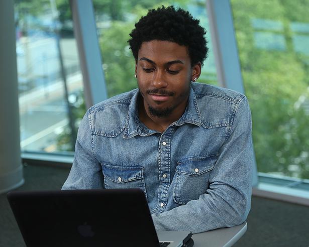A Kean University student works on a laptop.