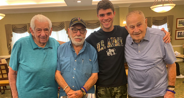 Kean student, Michael Naya, smiles for a photo with 3 World War 2 veterans.