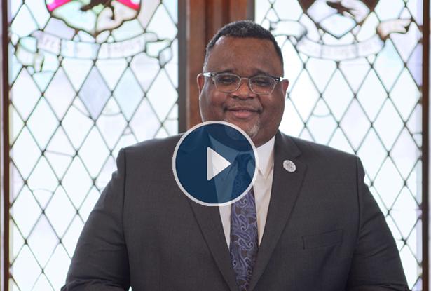 Kean University President Lamont O. Repollet, Ed.D., with a video play button overlay.