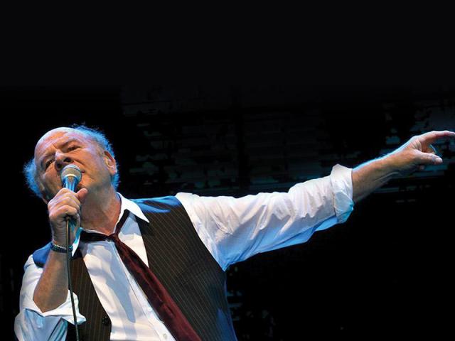 Garfunkel singing on stage with hand extended