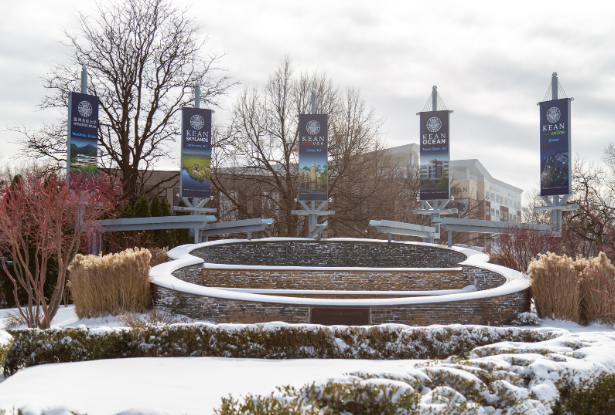 Flags from Kean University's five campuses fly at a fountain on the Union campus in the snow.