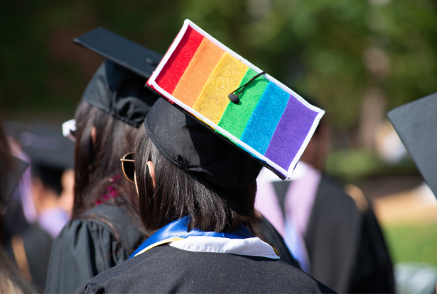 A student wears a graduation cap with the LGBTQIA+ rainbow flag on it at commencement