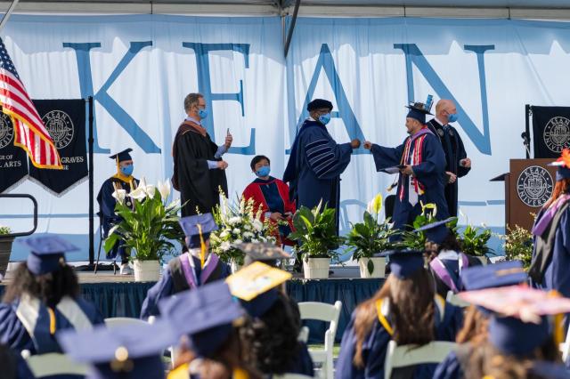 Kean MGC student fist bumps Pres. Repollet on stage