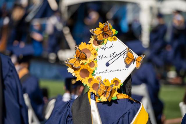 View of Kean Class of 2021 graduate motor board reads "And the story continues" decorated with sunflowers and yellow butterflies.