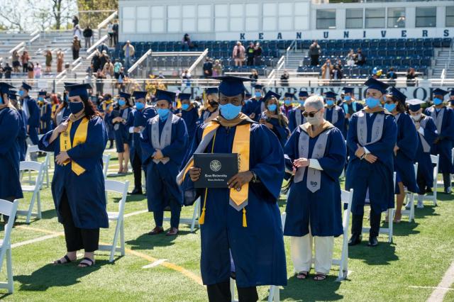 A proud grad shows off their diploma at Kean's CBPM commencement ceremony.