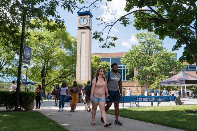 Students walk on Kean's campus in Union, with the clock tower behind them.