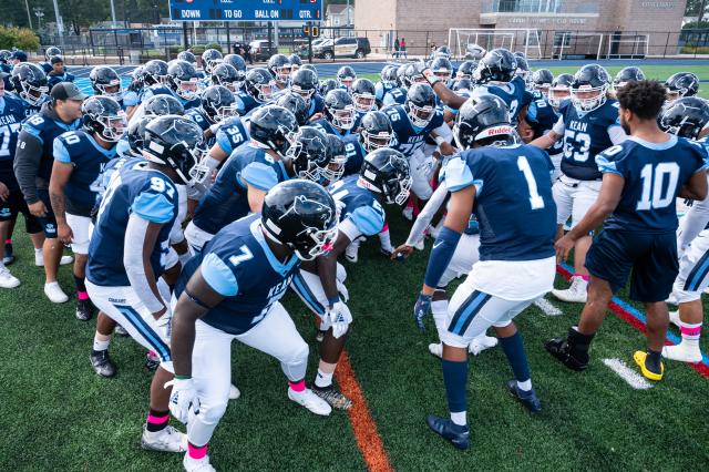 The football team in a group huddle chanting and getting ready to play at Homecoming 2021.