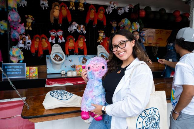 A student posing with a llama plushie after winning one of the carnival games at Homecoming 2021.