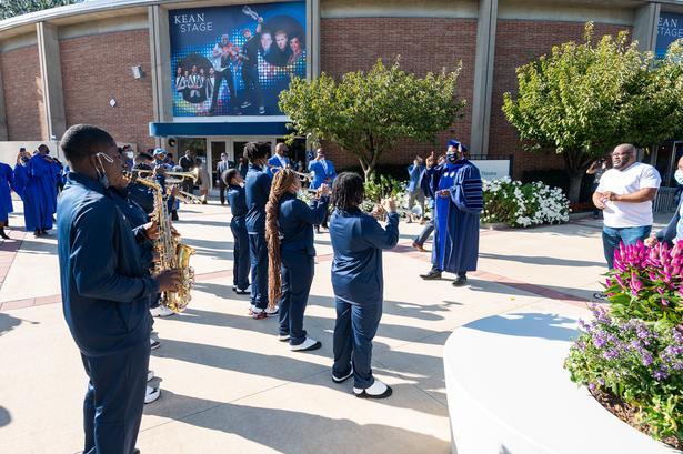 Dr. Repollet playfully directs a marching band outside of Wilkins Theatre