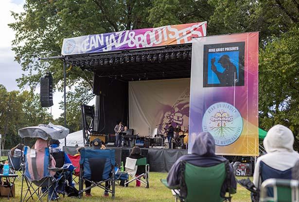 Musicians perform onstage at the Jazz & Roots Music Festival as the audience looks on.