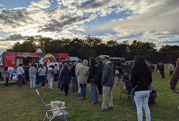 A group of people lining up at a food truck at the Jazz Roots Festival.