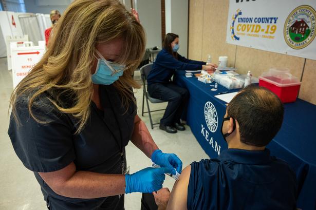 A nurse gives a vaccine to a male patient at Kean University's Union County vaccination site.