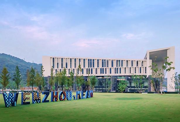 Wenzhou-Kean University's architecture building, with blue sky and Wenzhou-Kean in large letters on the lawn.