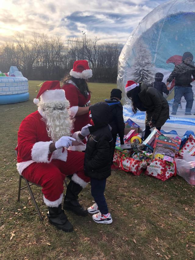 Santa giving out toys to children at a volunteer event.