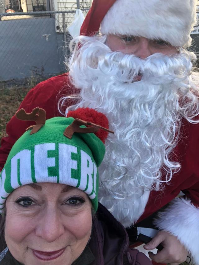 Dr. Norma Bowe is smiling for a photo with Santa at her volunteer event for her organization, Be The Change. 