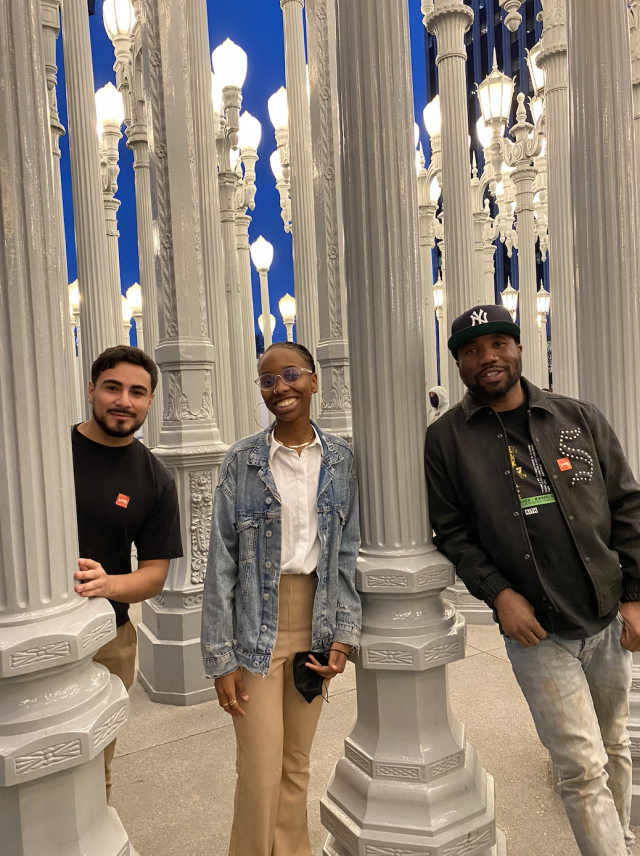 Nazira Goldware, Brandon Bravo, and Knowledge Bennett posing for a photo with the lamp post museum exhibit.