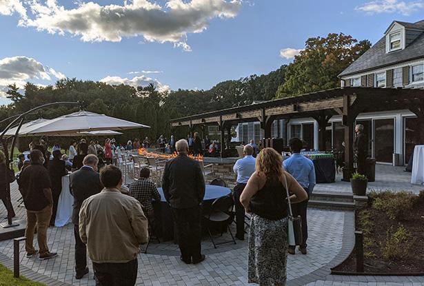 A large group of people walking on a gray stone patio.