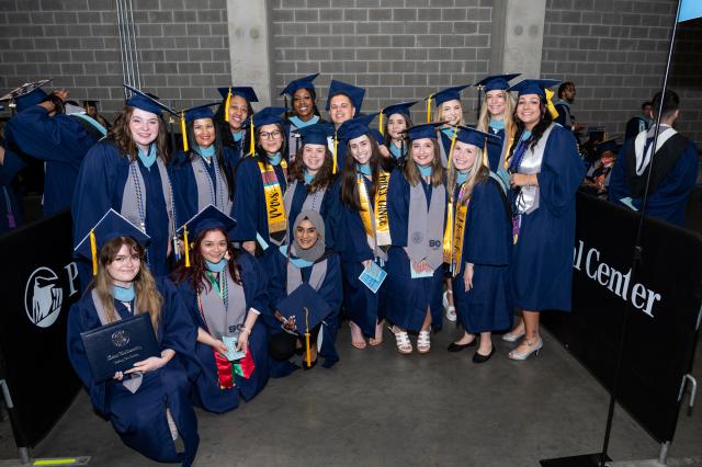 A group of Kean graduates in blue caps and gowns.