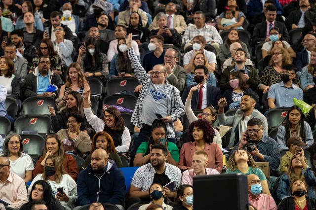 Audience members stand and wave as graduates enter the Prudential Center.
