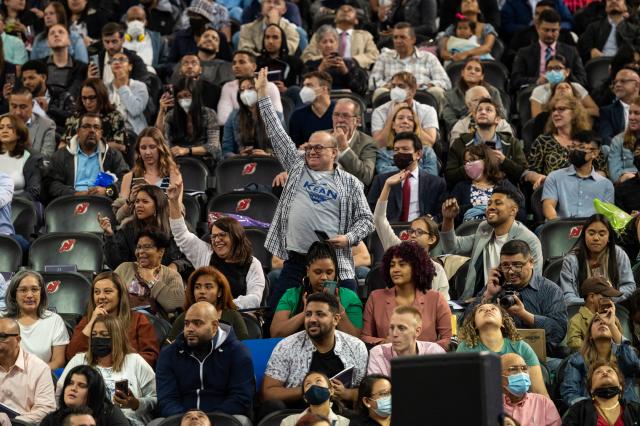 Audience members stand and wave as graduates enter the Prudential Center.