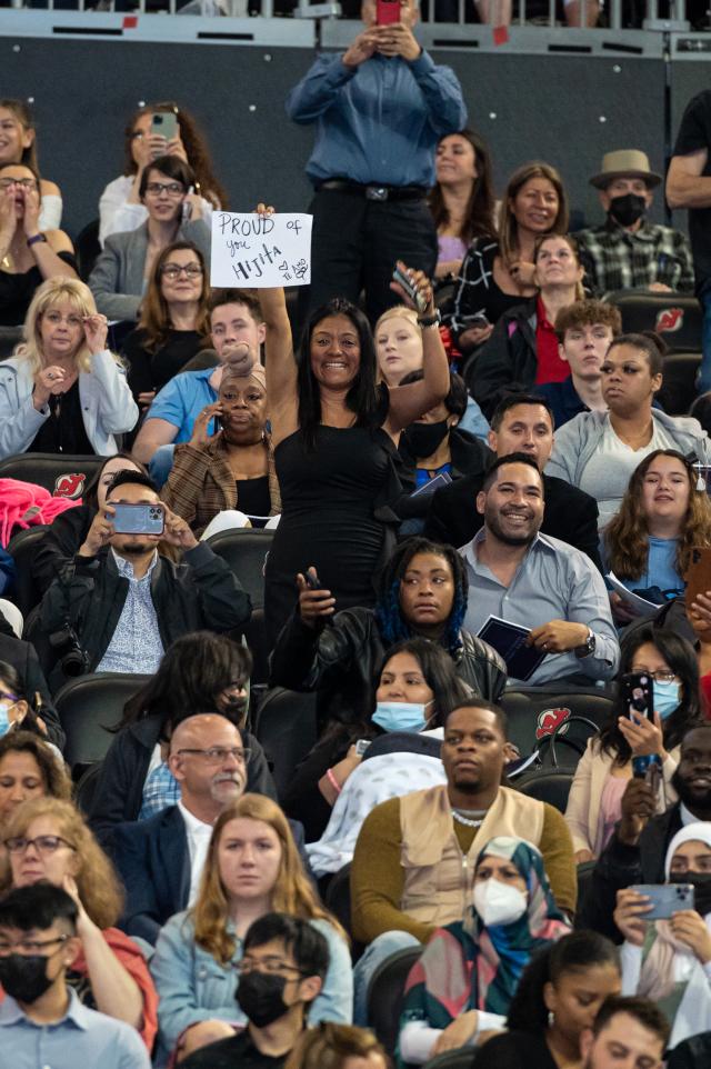 A woman in the audience holds a sign reading, "I'm proud of you."