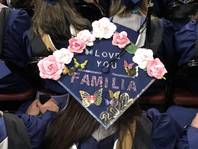 A decorated graduation cap reads, "Love You Familia."