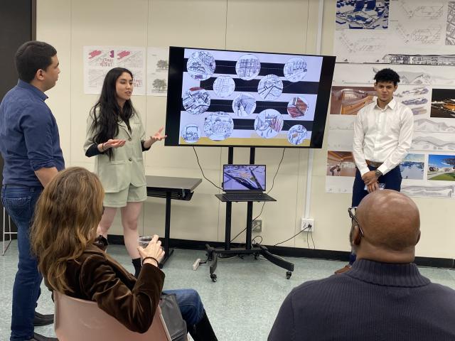 Two students stand before a big screen, making a presentation.