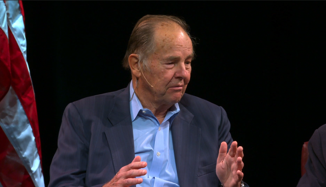 Former N.J. Governor Tom Kean gestures while sitting on stage.