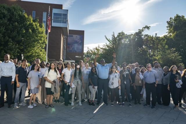 Kean President Repollet stands with a diverse group of Kean employees, with the sun gleaming behind them.