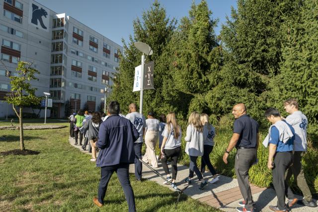 A diverse group of Kean employees is seen from behind walking on Cougar Walk.