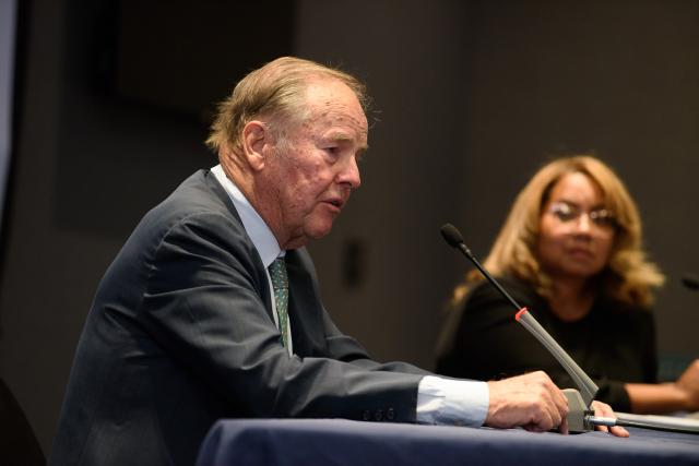 Former N.J. Governor Tom Kean speaks at a table; in the background is Kean Senior VP Sancha Gray.