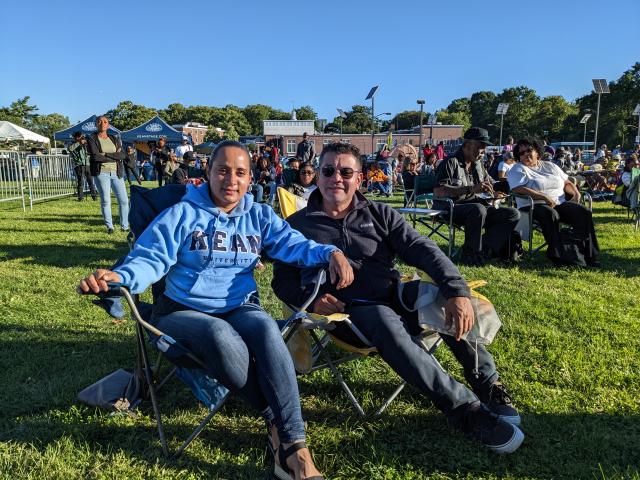 A young couple sits on lawn chairs. The woman wears a blue Kean sweatshirt.