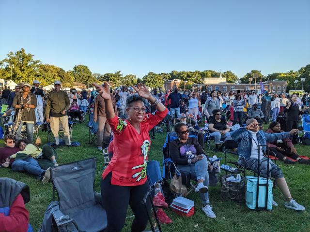 A woman dances with her arms in the air at the Jazz and Roots Festival.