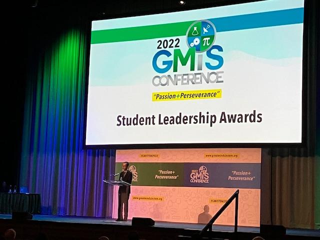 Xavier Amparo speaks at a lecturn on stage, with a screen behind him reading 2022 GMiS Student Leadership Awards