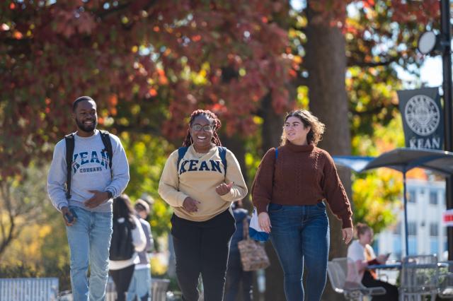 Three students walk across campus on a fall day 2022