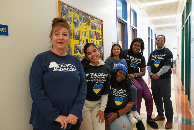 A hallway with a diverse group of students, with their professor, posing.