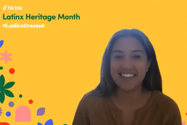 A young hispanic woman smiles. Latinx Heritage Month is displayed.