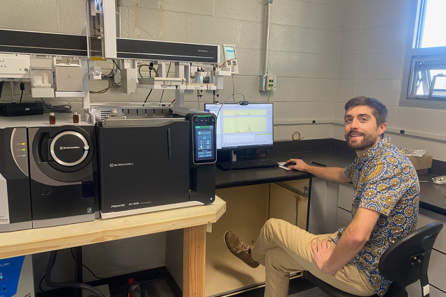 Scott LaFontaine sits before a laptop computer and sophisticated scientific equipment