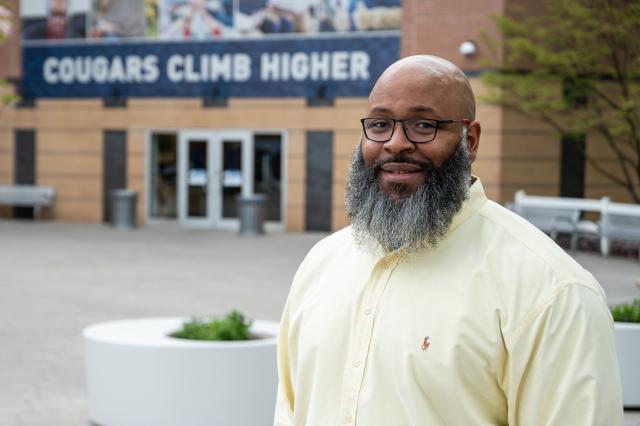 Former NY Giant Kareem McKenzie in front of Cougars Climb Higher sign on campus