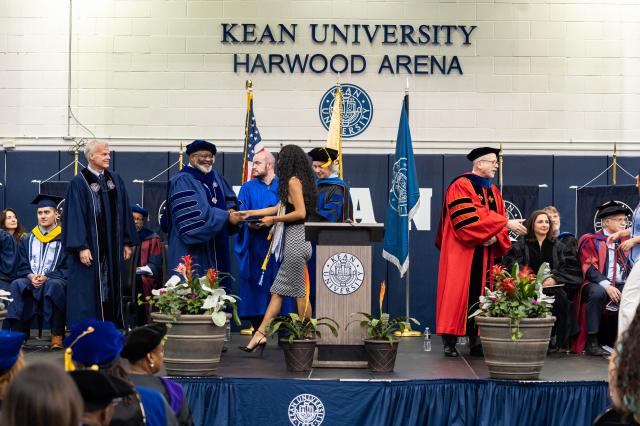 President Repollet shakes a woman graduates hand on stage