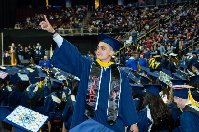 Kean graduate gestures toward the crowd