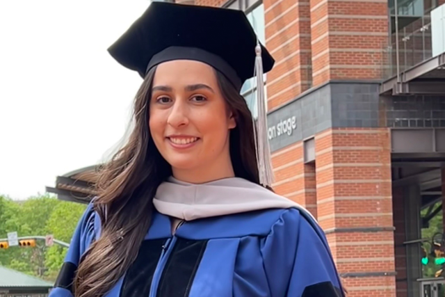 Elizabeth Del Pino, in her commencement gown and doctoral tam, smiles outside the New Jersey Performing Arts Center.