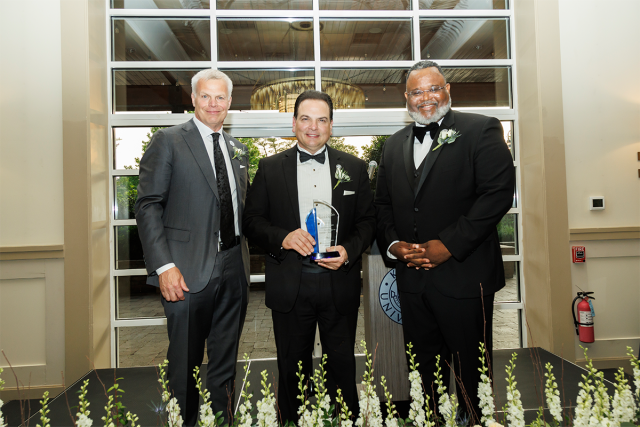 BOT Chair Steve Fastook, Senate President Nicholas Scutari, holding an award, and Kean President Lamont Repollet pose together.