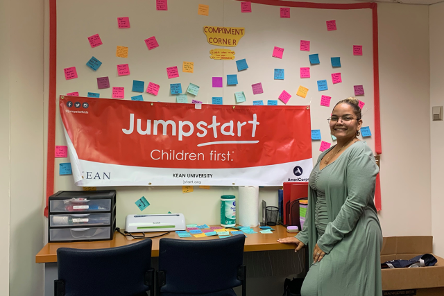 Kean alumna Yoleiny Grullon stands at the Jumpstart office bulletin board